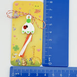 Martisor pentru Copii, Jolie, Model GHIOCEL cu BUBURUZA, din Cauciuc, cu Snur Impletit Alb/Rosu, Ambalaj Carton cu